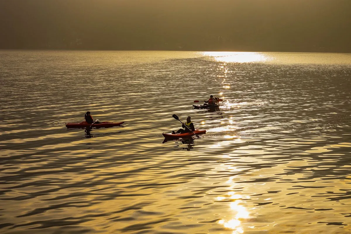 Personas en kayak sobre un lago de Bariloche con la luz del atardecer